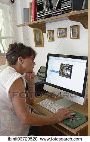 Stock Image - "Woman, mid 60s, using a computer". Fotosearch