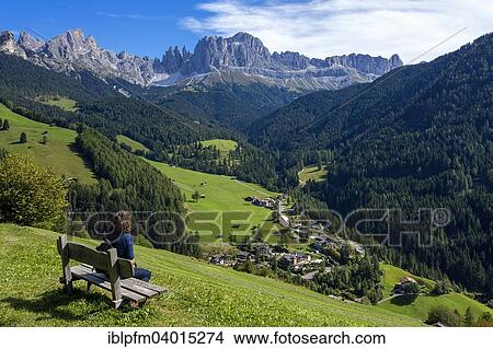 "Woman on bench, behind the Rose Garden Mountain group with village, Tiers, South Tyrol, Italy, Europe" View Large Photo Image Picture - "Woman on bench, behind the Rose Garden Mountain group with village, Tiers, South Tyrol, Italy, Europe". Fotosearch
