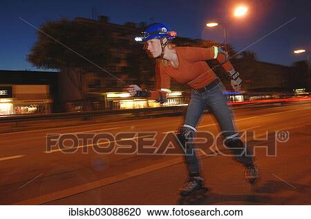 Stock Image - "Woman on inline skates wearing a helmet and lights at night, Laim, Furstenriedersrasse, Munich, Upper Bavaria, Bavaria, Germany, Europe". Fotosearch