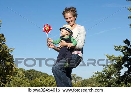 "Woman passing a pinwheel to a young boy, symbolic image for environmental education, alternative energy and sustainability" View Large Photo Image Stock Photography - "Woman passing a pinwheel to a young boy, symbolic image for environmental education, alternative energy and sustainability". Fotosearch