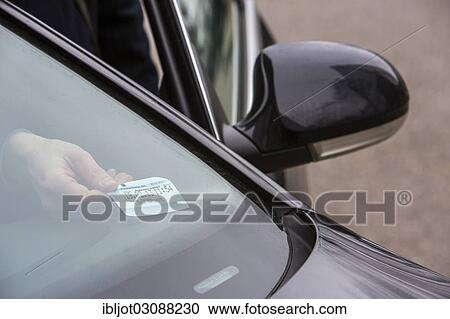 Stock Image - "Woman placing a parking ticket in a visible location in her car, Essen, North Rhine-Westphalia, Germany, Europe". Fotosearch