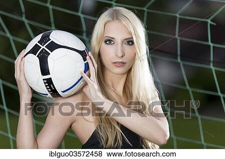 Stock Photo - Woman posing with a football in a goal. Fotosearch