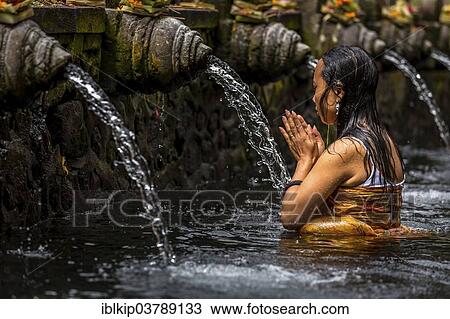 Stock Image - "Woman praying in a purifying pool, Tirta Empul Temple, Bali, Indonesia, Asia". Fotosearch