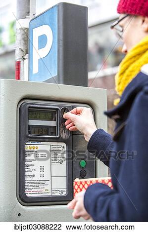 Stock Image - "Woman purchasing a parking ticket from a parking ticket vending machine, inner-city public parking, Essen, North Rhine-Westphalia, Germany, Europe". Fotosearch