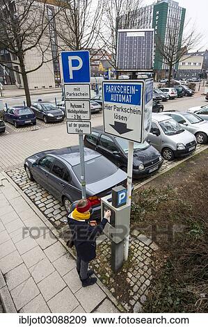 Stock Photo - "Woman purchasing a parking ticket from a solar powered parking ticket vending machine, inner-city public parking, Essen, North Rhine-Westphalia, Germany, Europe". Fotosearch