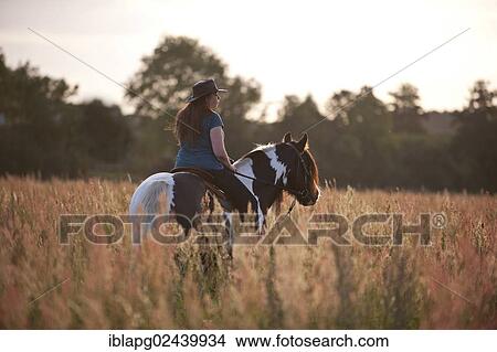 Picture - Woman riding an Irish Tinker across a meadow. Fotosearch
