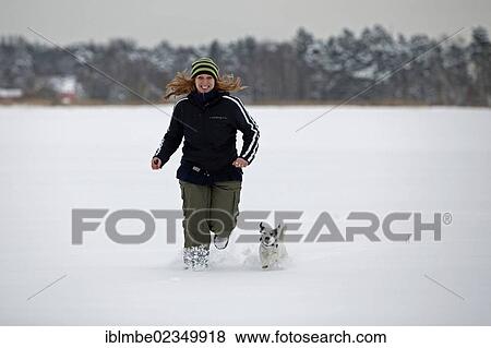 Woman running with a small dog through deep snow View Large Photo Image Stock Photo - Woman running with a small dog through deep snow. Fotosearch
