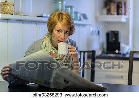 "Woman sitting at the kitchen table reading the newspaper, with an astonished look, Germany, Europe" View Large Photo Image Stock Image - "Woman sitting at the kitchen table reading the newspaper, with an astonished look, Germany, Europe". Fotosearch