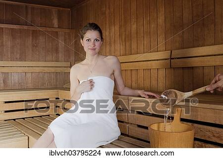 Picture - Woman sitting in a Finnish wood-fired sauna. Fotosearch