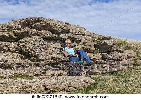 "Woman sitting in front of a rock and reading a book, island of Heligoland, Schleswig-Holstein, Germany, Europe" View Large Photo Image Stock Photo - "Woman sitting in front of a rock and reading a book, island of Heligoland, Schleswig-Holstein, Germany, Europe". Fotosearch