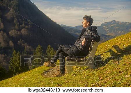 Stock Image - "Woman sitting on a bench, relaxed, sunbathing, Gerstruben near Oberstdorf, Allgaeu, Bavaria, Germany, Europe, PublicGround, Europe". Fotosearch