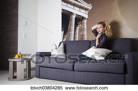 Woman sitting on a couch in a hotel room View Large Photo Image Stock Photography - Woman sitting on a couch in a hotel room. Fotosearch