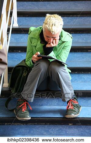 Woman sitting on stairs reading an e-book View Large Photo Image Stock Photograph - Woman sitting on stairs reading an e-book. Fotosearch