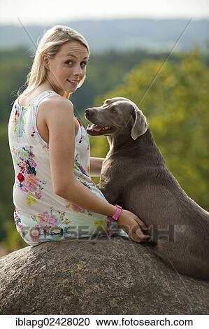 Woman sitting with a Labrador Retriever on a stone View Large Photo Image Stock Image - Woman sitting with a Labrador Retriever on a stone. Fotosearch