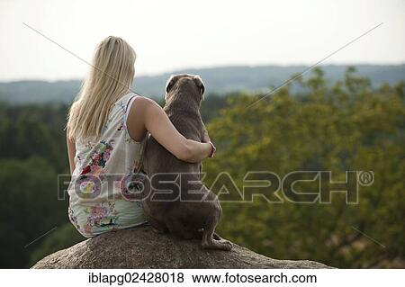 Stock Photo - Woman sitting with a Labrador Retriever on a stone. Fotosearch