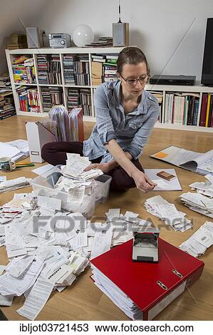 Stock Image - "Woman sorting documents, records, invoices and receipts on the ground, for the tax return". Fotosearch
