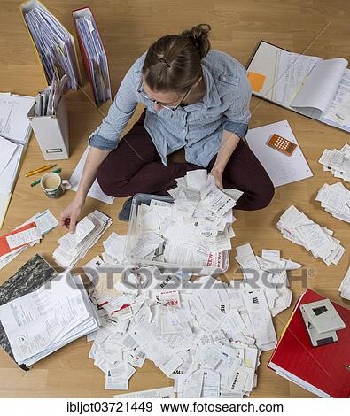 Stock Photo - "Woman sorting documents, records, invoices and receipts on the ground, for the tax return". Fotosearch
