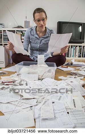 Stock Photograph - "Woman sorting documents, records, invoices and receipts on the ground, for the tax return". Fotosearch