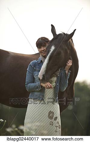 Woman standing beside a Hanoverian horse in a meadow View Large Photo Image Stock Photo - Woman standing beside a Hanoverian horse in a meadow. Fotosearch