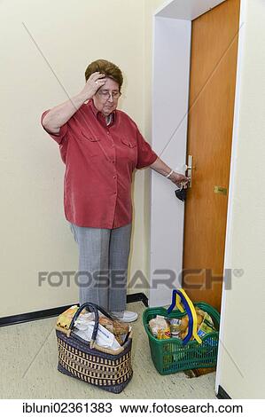 "Woman standing with full baskets of shopping in front of her apartment door, touching her forehead" View Large Photo Image Stock Image - "Woman standing with full baskets of shopping in front of her apartment door, touching her forehead". Fotosearch