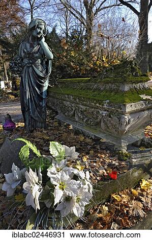 "Woman statue next to a mossy sarcophagus with artificial flowers and autumn leaves on the Ostfriedhof or East Cemetery, Munich, Bavaria, Germany, Europe" View Large Photo Image Stock Image - "Woman statue next to a mossy sarcophagus with artificial flowers and autumn leaves on the Ostfriedhof or East Cemetery, Munich, Bavaria, Germany, Europe". Fotosearch