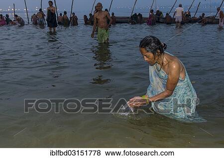 Stock Photo - "Woman taking a bath in the Sangam, the confluence of the rivers Ganges, Yamuna and Saraswati, in the early morning, Kumbha Mela mass Hindu pilgrimage, Allahabad, Uttar Pradesh, India, Asia". Fotosearch