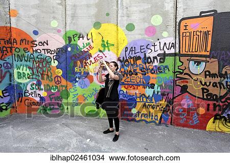 "Woman taking a photograph at a graffiti-covered defense wall, Palestinian side, between Bethlehem, the West Bank and Jerusalem, Israel, Middle East, Orient, Asia" View Large Photo Image Picture - "Woman taking a photograph at a graffiti-covered defense wall, Palestinian side, between Bethlehem, the West Bank and Jerusalem, Israel, Middle East, Orient, Asia". Fotosearch