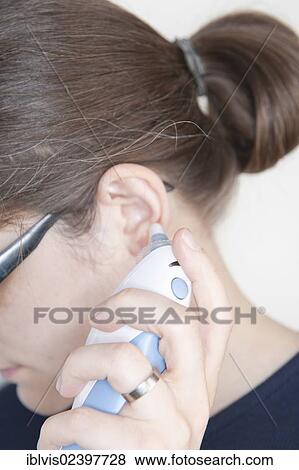 Woman using an ear thermometer View Large Photo Image Stock Photo - Woman using an ear thermometer. Fotosearch