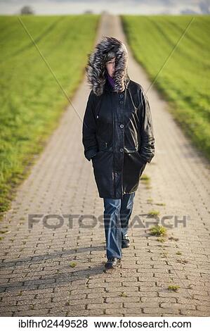 Stock Photo - "Woman walking on a field path, Grevenbroich, North Rhine-Westphalia, Germany, Europe". Fotosearch