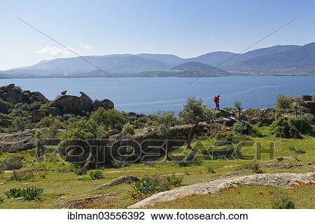 Stock Image - "Woman wearing a backpack while hiking at Lake Bafa, Lake Bafa, Mugla Province, Aegean region, Turkey, Asia". Fotosearch