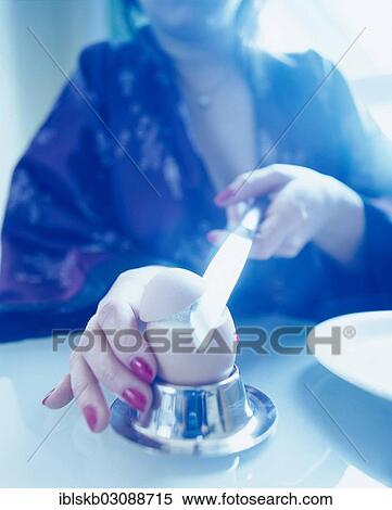Woman wearing a bath robe slicing off the top of a breakfast egg with a knife View Large Photo Image Stock Photography - Woman wearing a bath robe slicing off the top of a breakfast egg with a knife. Fotosearch