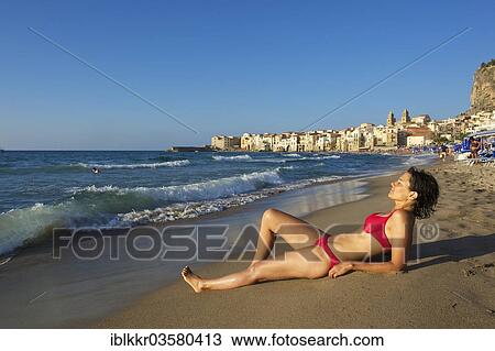 "Woman wearing a bikini, lying on a beach in front of the historic town centre, Cefalu, Province of Palermo, Sicily, Italy, Europe" View Large Photo Image Stock Image - "Woman wearing a bikini, lying on a beach in front of the historic town centre, Cefalu, Province of Palermo, Sicily, Italy, Europe". Fotosearch