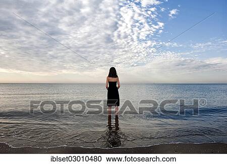 "Woman wearing a black dress standing in the water of the sea, moody clouds, Cavallino, Jesolo, Venedig, Italy, Europe" View Large Photo Image Stock Image - "Woman wearing a black dress standing in the water of the sea, moody clouds, Cavallino, Jesolo, Venedig, Italy, Europe". Fotosearch