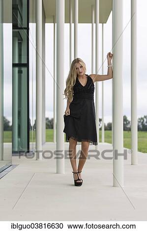 Woman wearing a black evening dress leaning against a column View Large Photo Image Stock Image - Woman wearing a black evening dress leaning against a column. Fotosearch