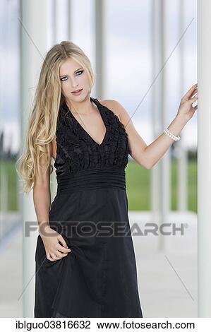 Woman wearing a black evening dress leaning against a column View Large Photo Image Stock Image - Woman wearing a black evening dress leaning against a column. Fotosearch