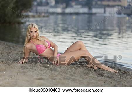 Woman wearing a pink bikini lying on a lakeside beach View Large Photo Image Stock Photo - Woman wearing a pink bikini lying on a lakeside beach. Fotosearch