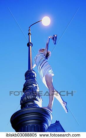 "Woman wearing a summer dress standing on street lamp and holding hershoes in the air, blue hour" View Large Photo Image Stock Photography - "Woman wearing a summer dress standing on street lamp and holding hershoes in the air, blue hour". Fotosearch