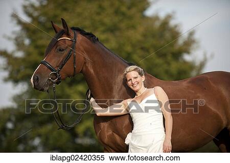 Woman wearing a wedding dress with a Hanoverian horse in a meadow View Large Photo Image Stock Photography - Woman wearing a wedding dress with a Hanoverian horse in a meadow. Fotosearch