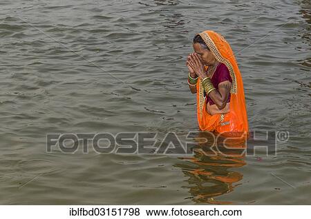 "Woman wearing an orange sari taking a bath in the Sangam, the confluence of the rivers Ganges, Yamuna and Saraswati, in the early morning, Kumbha Mela mass Hindu pilgrimage, Allahabad, Uttar Pradesh, India, Asia" View Large Photo Image Stock Photo - "Woman wearing an orange sari taking a bath in the Sangam, the confluence of the rivers Ganges, Yamuna and Saraswati, in the early morning, Kumbha Mela mass Hindu pilgrimage, Allahabad, Uttar Pradesh, India, Asia". Fotosearch