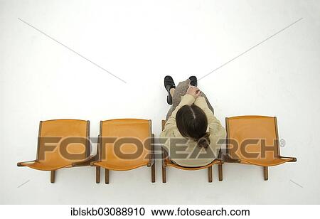 "Woman wearing conservative clothes sitting on one of a row of four orange chairs, bird's eye view" View Large Photo Image Stock Image - "Woman wearing conservative clothes sitting on one of a row of four orange chairs, bird's eye view". Fotosearch