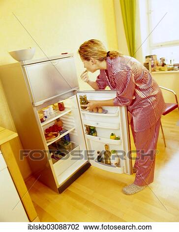 Woman wearing pyjamas standing at an open refrigerator and eating pickles View Large Photo Image Stock Image - Woman wearing pyjamas standing at an open refrigerator and eating pickles. Fotosearch