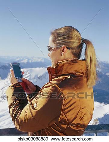 "Woman wearing winter clothes holding a cell phone over snowy mountain peaks, Zugspitze, Wetterstein mountain range, Eastern Alps, Garmisch-Partenkirchen, Upper Bavaria, Bavaria, Germany, Europe" View Large Photo Image Stock Photo - "Woman wearing winter clothes holding a cell phone over snowy mountain peaks, Zugspitze, Wetterstein mountain range, Eastern Alps, Garmisch-Partenkirchen, Upper Bavaria, Bavaria, Germany, Europe". Fotosearch