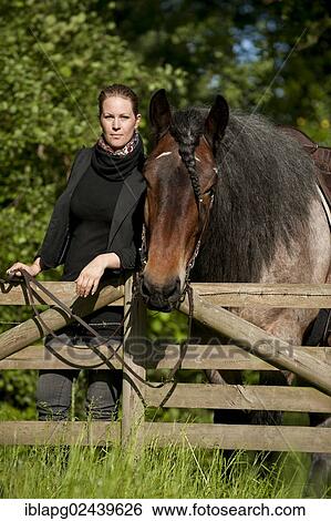 Stock Photograph - Woman with a Belgian Draft Horse at a fence. Fotosearch