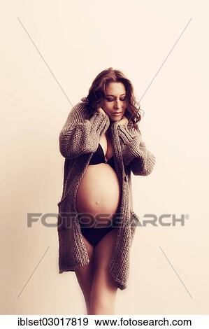 Stock Photo - "Woman with a pregnant belly, in underwear and a cardigan". Fotosearch
