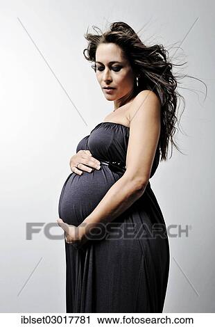 Stock Image - Woman with a pregnant belly wearing a dress. Fotosearch