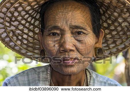 Stock Image - "Woman with a traditional facial tattoo and ear jewelry, ethnic group of the Chin, ethnic minority, portrait, Rakhine State, Myanmar, Asia". Fotosearch