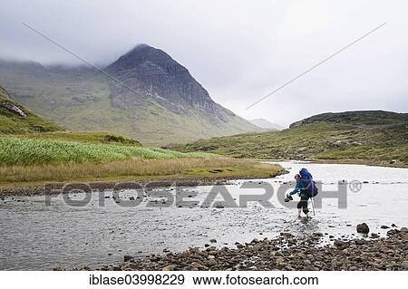 "Woman with backpack crossing river Abhainn Camas Fhionnairigh, with Sgurr Hain behind, Camasunary, Isle of Skye, Scotland, United Kingdom, Europe" View Large Photo Image Stock Photo - "Woman with backpack crossing river Abhainn Camas Fhionnairigh, with Sgurr Hain behind, Camasunary, Isle of Skye, Scotland, United Kingdom, Europe". Fotosearch