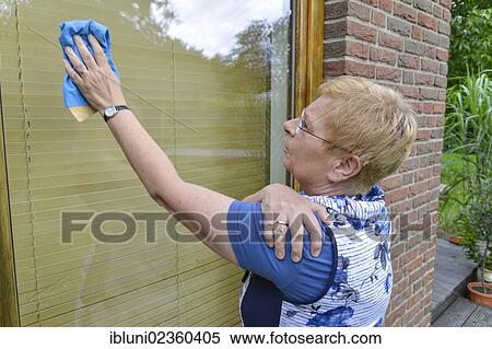 Woman with joint pain in her shoulder cleaning a window View Large Photo Image Stock Photography - Woman with joint pain in her shoulder cleaning a window. Fotosearch