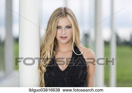 Stock Photo - "Woman with long blond hair leaning against a column, portrait". Fotosearch