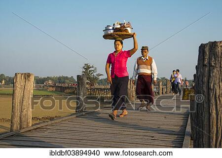 "Woman with tanaka on her face carrying food on her head on a teak bridge, U Bein Bridge, over Thaungthaman Lake, Amarapura, Mandalay Division, Myanmar, Asia" View Large Photo Image Stock Image - "Woman with tanaka on her face carrying food on her head on a teak bridge, U Bein Bridge, over Thaungthaman Lake, Amarapura, Mandalay Division, Myanmar, Asia". Fotosearch